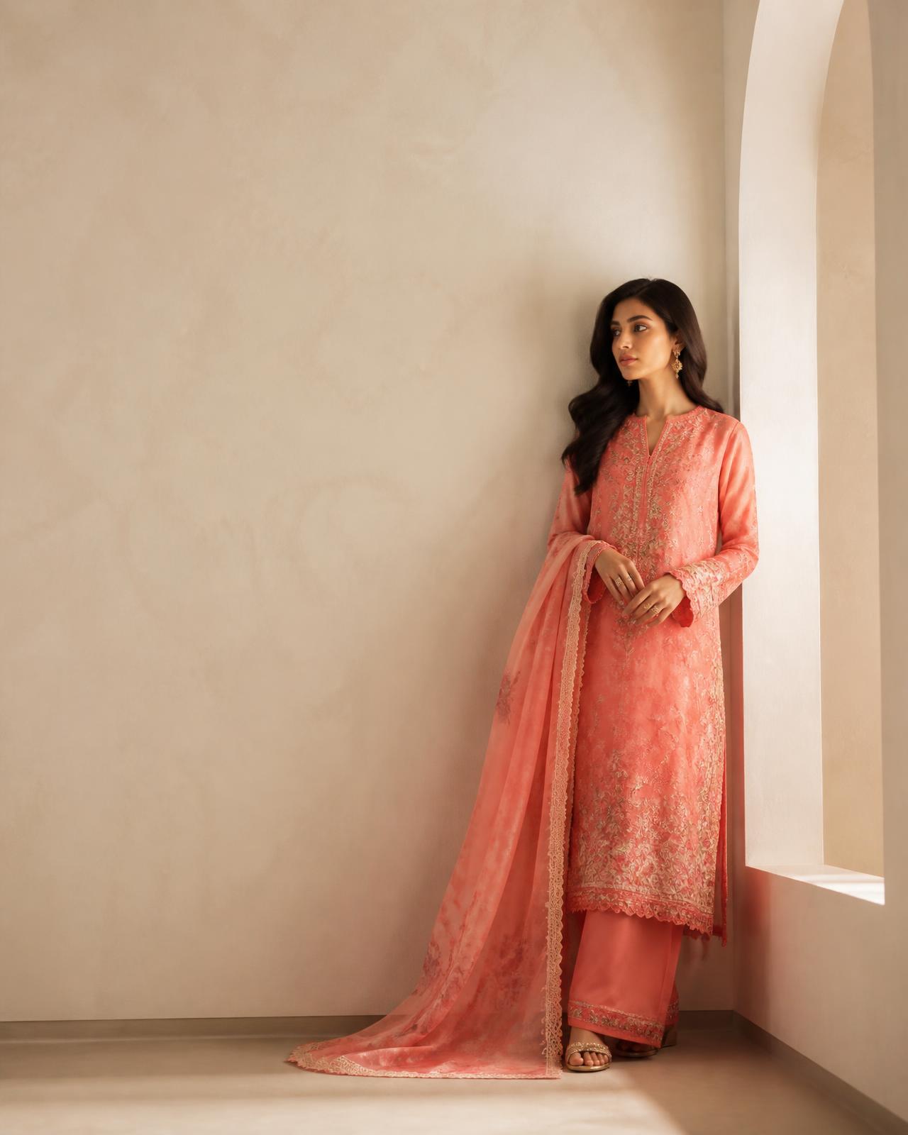 Model wearing a coral embroidered unstitched suit